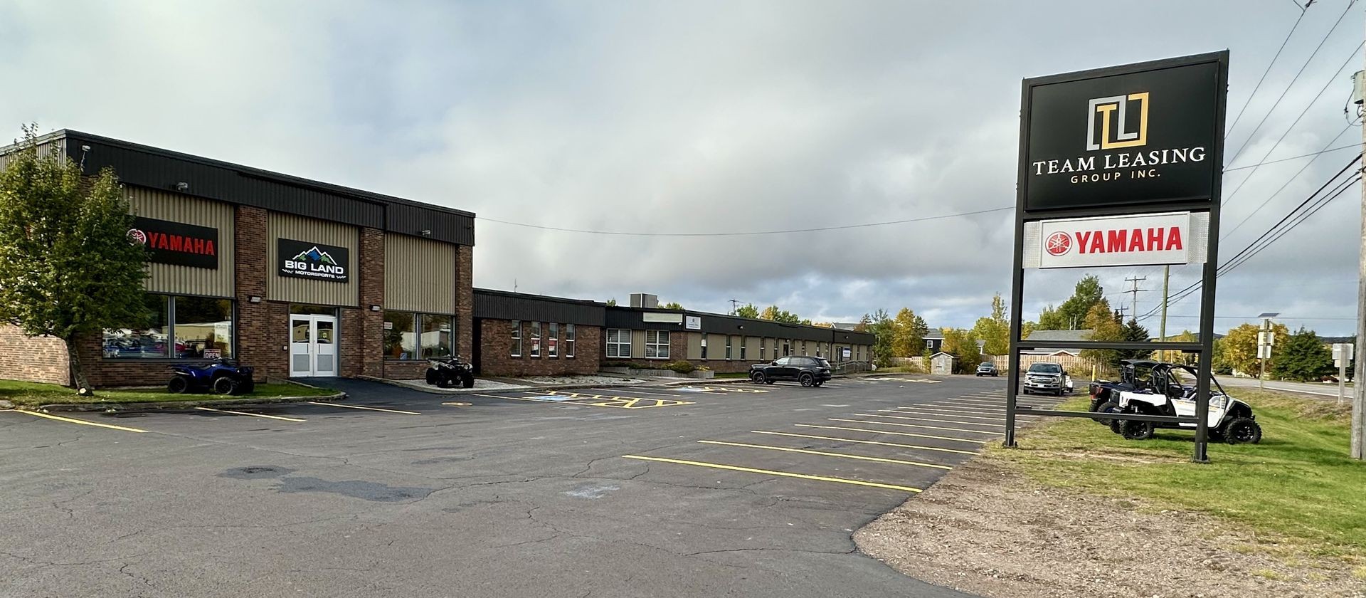 Exterior view of Big Land building with Yamaha and Team Leasing signs, parking lot in foreground.